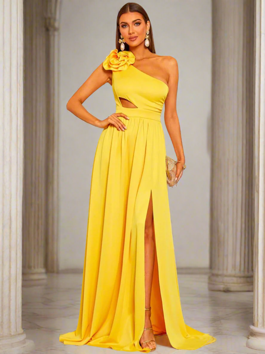 A woman wearing a yellow one shoulder, floral applique, cutout maxi dress with a high slit.